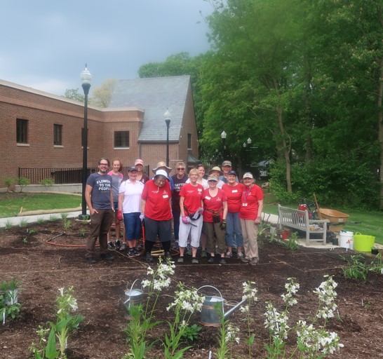 A group of volunteer gardeners gather among recently planted flowers