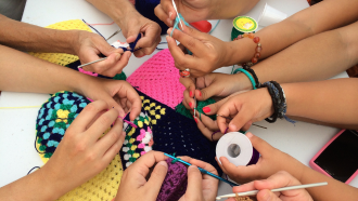 Young people's hands work on fiber art crafts