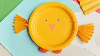 A child's craft of a bird made from a yellow paper plate.