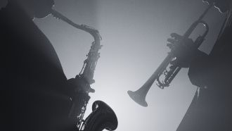 Black and white image of two jazz musicians - one playing saxophone, the other playing the trumpet.