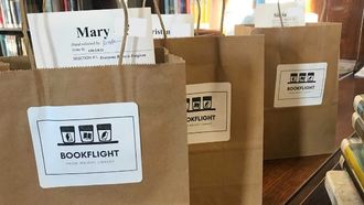 three brown bags with books and bookflight sticker lined up ready for pickup