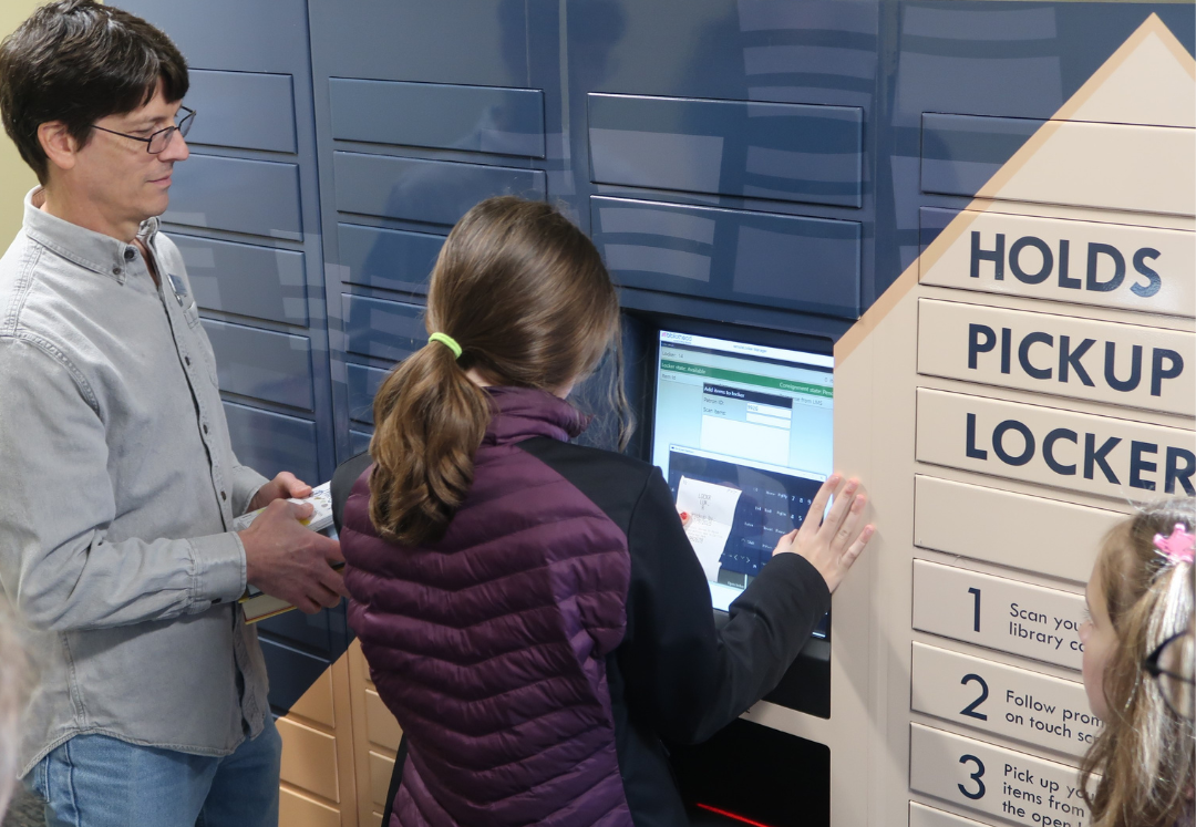 Patron uses Holds Pickup Locker at Wright Library to retrieve books on hold.