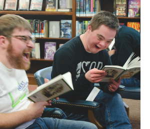 Two young men laugh while reading at the Next Chapter Book Club