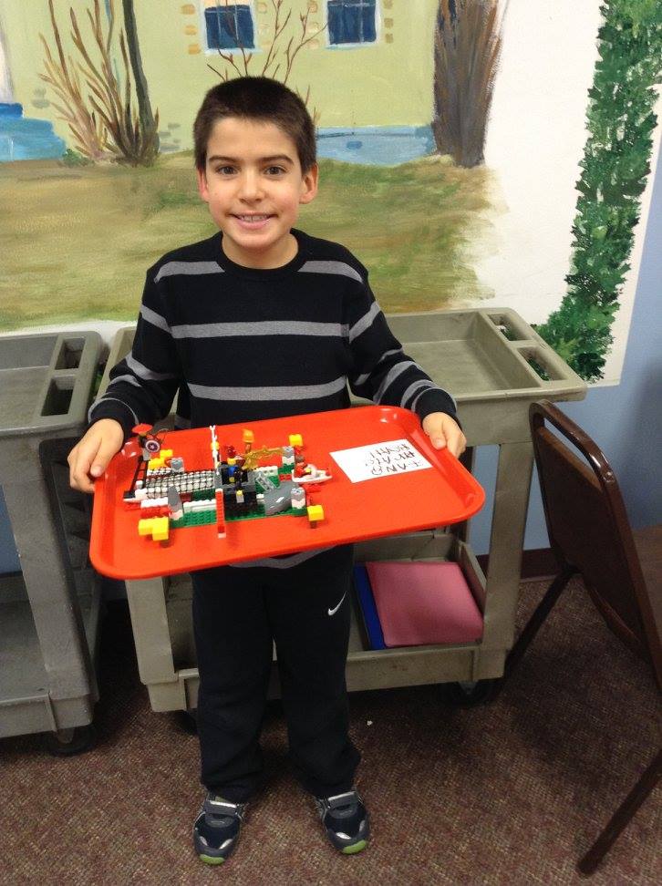A young library patron holds up his LEGO creation.